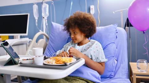 child in hospital bed eating 