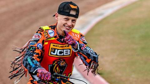 Cooper Rushen points to a camera after a race