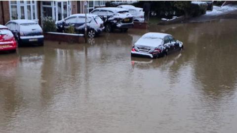 Cars in standing water with snowfall on car roofs