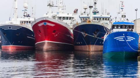 Four boats in water berthed at harbour