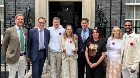 Georgie Maynard (in the middle with glasses on) and her brother, Witney MP Charley Maynard (on her left, in a suit), in front of 10 Downing Street, with other campaigners. She is holding a petition, calling for more research into brain cancer.