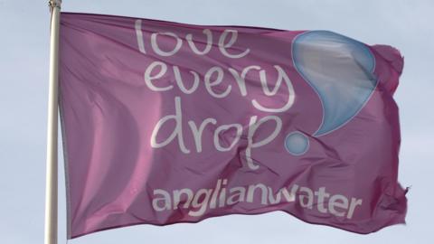 A purple flag with the slogan "Love every drop" and the Anglian Water logo on it.