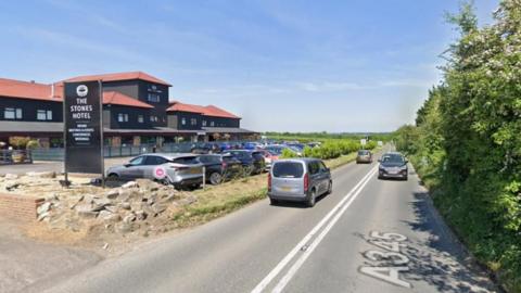 A Google Streetview image of the A345 outside the Stones Hotel with a large green hedge along the edge of the road.