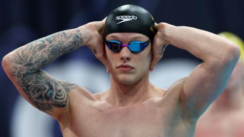 Matt Richards with hands on his swim cap and googles preparing to start