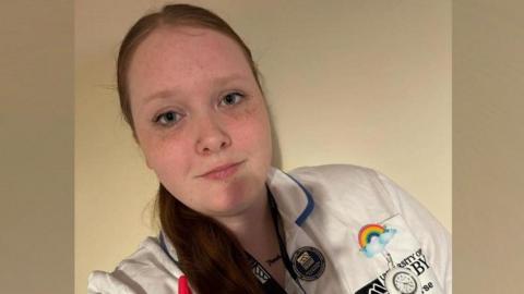 Rosie Thorpe, who has long red-brown hair, wearing a student nurse's uniform