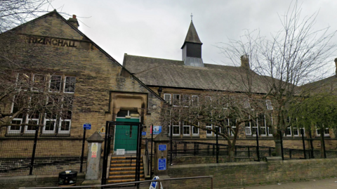 Front view of Frizinghall Primary School, with the school's name built into the brickwork on the left-hand side.