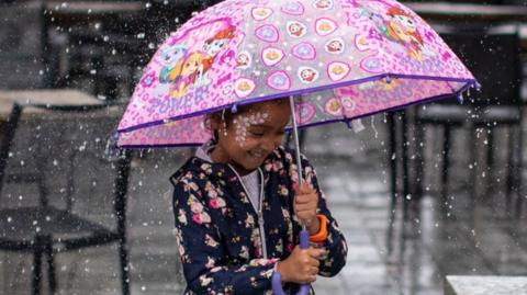 Girl holding a pink umbrella in the rain