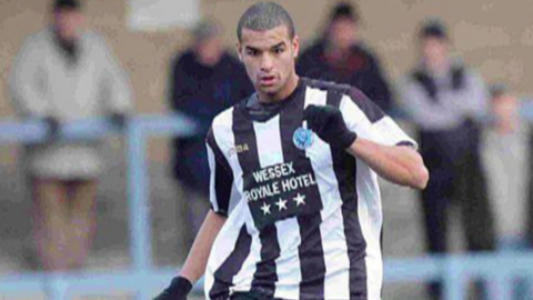 A footballer wearing a black and white football shirt