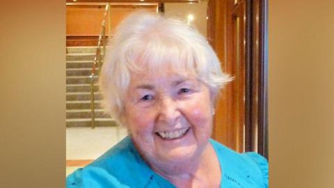 Lorraine Sencicile, pictured smiling at the camera. She has short white hair and is wearing a bright blue top. 