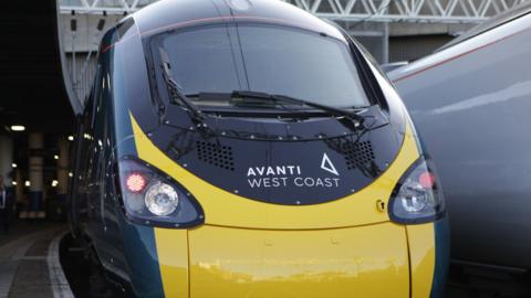 A black and yellow Avanti west coast train parked in a station 