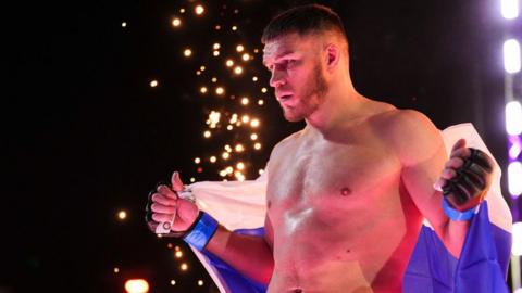 Vadim Nemkov enters the cage wrapped in a Russian flag