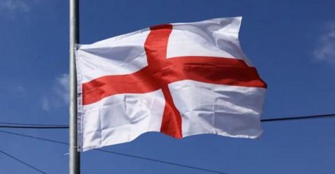 A St George's Cross flag flying against a blue sky