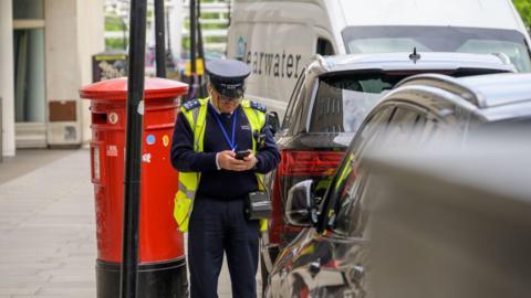 stock image of traffic warden booking a ticket