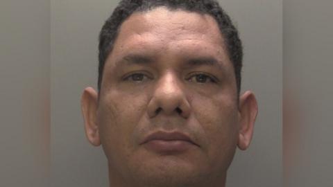 Custody photograph of Didier Reyes  he has short black hair and is wearing a grey T-shirt