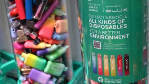Recycling bin filled with single-use disposable vapes in different shapes and colours