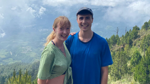 Leila and Louis posing for a photo high up a mountain with the valley behind them