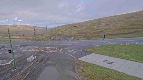 The Mountain Road at the junction at the Bungalow showing the electric tram tracks and other infrastructure with the hills sloping into the Laxey Valley behind.