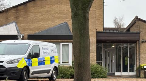 A white police forensics van is parked outside of an accommodation block on Somerleyton Street in Norwich. In the foreground of the picture is a grey sign which says SOMERLEYTON HOUSE, PROFESSIONAL AND STUDENT ACCOMMODATION.