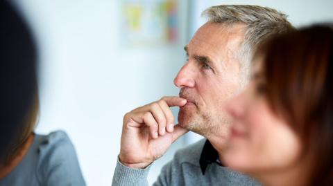 A picture of a grey-haired man who is listening thoughtfully. 