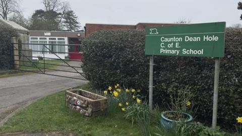 A green school sign next to the entrance of a school