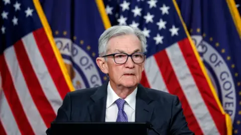 Federal Reserve Chair Jerome Powell stands in front of an American flag