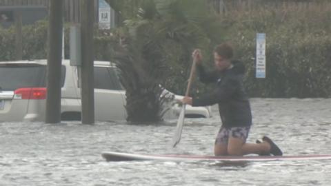 Boy is paddling on a surfboard.