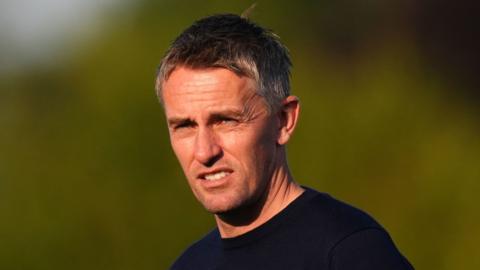 Headshot of Kieran McKenna who looks slightly to his left, squints and slightly grimaces. he wears a navy top.