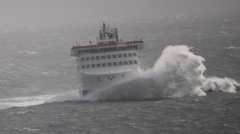 The Manxman, a large boat, on choppy waters with a large wave crashing to the right.