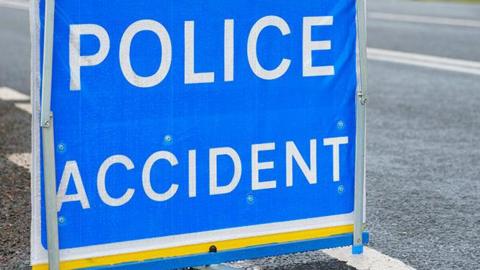 A police accident sign, with the words POLICE ACCIDENT in white bold letters on a blue background, on a road.