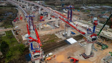 Two large viaducts being put into place over a railway line. There are cranes, earth-moving vehicles around the concrete bases of these huge, bridge-like structures.