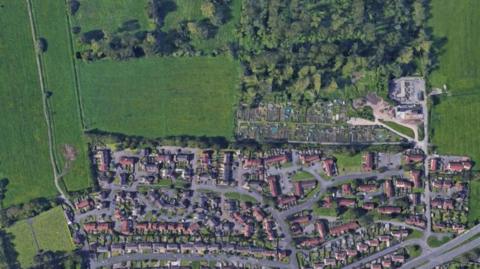 A screengrab from Google Maps showing an aerial view of the northern part of the village of Street in Somerset. There are lots of houses in the bottom part of the image with some green fields at the top, where the houses will be built.
