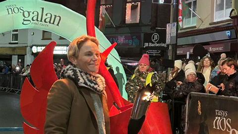 Jess Fishlock, pictured in the street of Mountain Ash town centre, holds a lit torch used to herald the start of the annual race