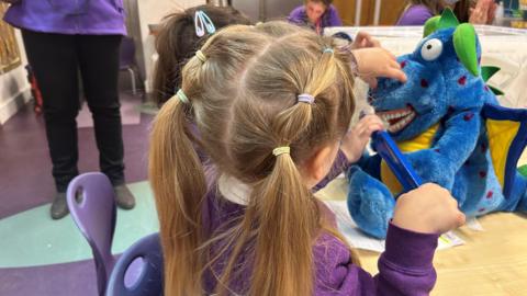 Children brushing Dylan the dragon's teeth 