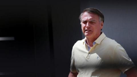 Brazil's former president Jair Bolsonaro walks at his residence in Brasilia, Brazil, 3 September 2025.  He is wearing a pale yellow polo shirt. His brow is furrowed. 