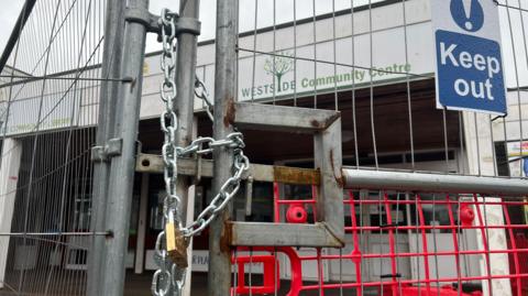 Chains and a padlock on steel gates outside Westside Community Centre.