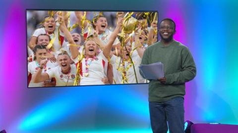 De-graft in the studio with England's winning rugby team in the screen