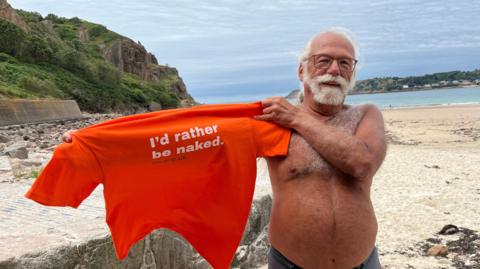 Ross Mantle on beach holding T-shirt