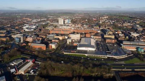 An aerial view of Oldham, with a range of buildings and roads seen from above.