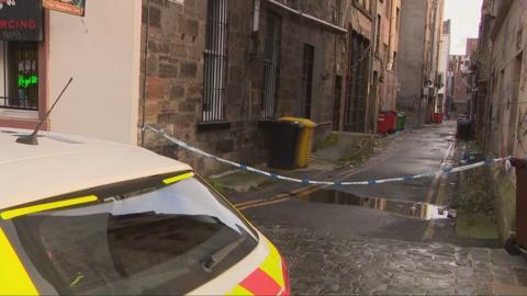 A lane covered with police tape. Part of a police car is also visible.