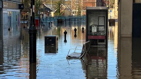 Chippenham town centre after flooding from Storm Bert. Bollards along the street can be seen, as well as businesses along either side of the road. They are all closed due to the flood.