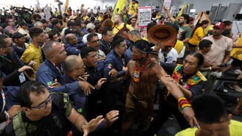 Yellow-shirted protesters clash with security guards inside the conference venue