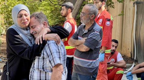 Relatives of victims react as search and rescue team members work to find bodies under the rubble of buildings destroyed in an Israeli airstrike in Ain el-Delb, Lebanon (30 September 2024)