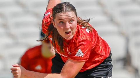 Grace Ballinger wearing an orange top goes through her bowling action