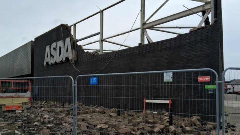A picture of the outside of the Asda store in Hayle. It is a large brick building with the logo on it.