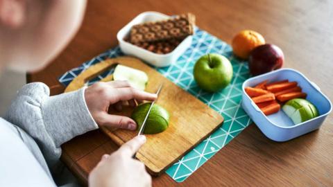 Someone cutting up an apple on a chopping board.