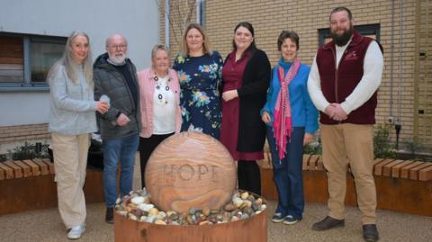 People stood around water feature which has the word HOPE on it