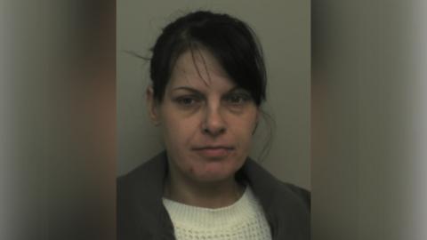 Tracey Makings with medium-length dark hair, a white jumper and a grey jacket, looking at the camera in a police custody photo.