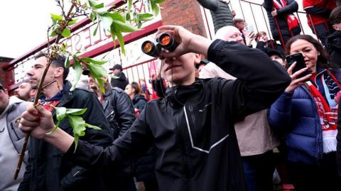 A fan is seen using binoculars outside the stadium prior to the Championship play-off semi-final match between Middlesbrough and Southampton at Riverside Stadium