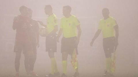 The officials speaking to the managers with fog making it hard to see any of the people in the photograph (it's basically an illustration of fog)