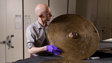 Dr Matthew Knight holding up a circular bronze shield found in a field in Beith more than 200 years ago.